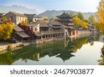 the traditional chinese buildings at riverside with reflection and mountain in distance, Beijing, Gubei water town