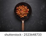 Traditional Chinese dish kung pao chicken in wok pan on dark background top view