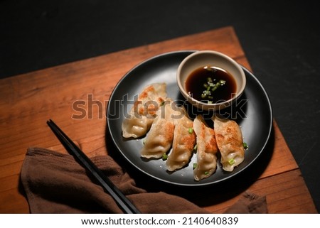 Traditional Chinese food cuisine, Fried dumplings or Gyoza served with special homemade sauce on a wood table with brown napkin and chopstick.