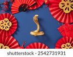 Traditional Chinese New Year decorations on a blue background with red paper fans, gold snake, and festive ornaments. Lunar New Year 2025, Year of the Snake concept.