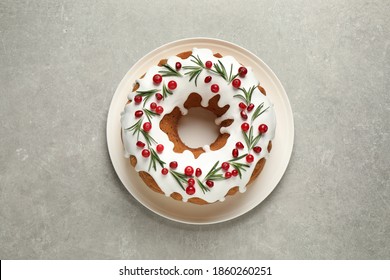 Traditional Christmas cake decorated with glaze, pomegranate seeds, cranberries and rosemary on light grey table, top view