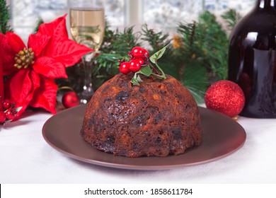 Traditional Christmas pudding with holly on top on the wooden background.
