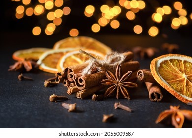 Traditional Christmas spices and dried orange slices on black background with defocus lights. Cinnamon sticks, star anise and cloves - Powered by Shutterstock