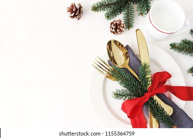 Traditional Christmas table place setting. Golden cutlery, linen napkin, spruce branches and cup of milk. Pine cone and red ribbon decoration. Holidays background. Flat lay, top view with copy space. - Powered by Shutterstock