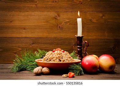 Traditional Christmas treat of the Slavs on Christmas eve kutia. Fir branch, apples, candle on wooden background. Place for text