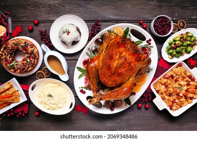 Traditional Christmas turkey dinner. Top view table scene on a dark wood background. Turkey, potatoes and sides, dressing, fruit cake and plum pudding. - Powered by Shutterstock