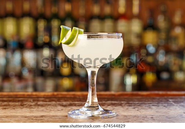 Traditional cocktail daiquiri, image for the menu.\
decorated with lime at bar background. Background blurred with soft\
focus. Space for\
text