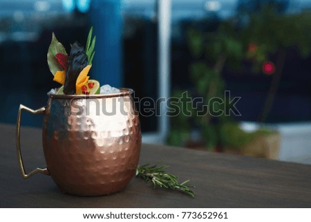 Traditional cocktail in modern serving. Soft drink with vodka, ginger beer and lime juice. Cold beverage in copper cup on wooden table with copy space. Mockup for moscow mule recipe