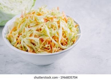Traditional coleslaw salad with fresh sliced carrots and cabbage in a white bowl with copy space
