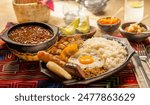 Traditional Colombian dish Bandeja Paisa with fried egg, beans, rice, chorizo, and pork rind served on a rustic table setting.