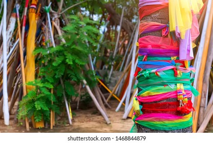 The traditional colorful fabrics tied on the tree in the Thai Buddhist Temple for praying with mini colorful garland