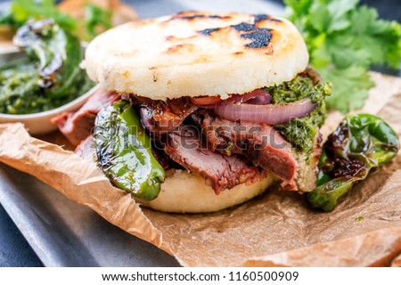 Traditional Columbian arepa con carne desmechada with shredded beef steak and aji criollo as closeup on a backing paper 