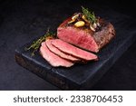 Traditional Commonwealth Sunday roast with sliced cold cuts roast beef with garlic and salt as close-up on a rustic charred wooden board 