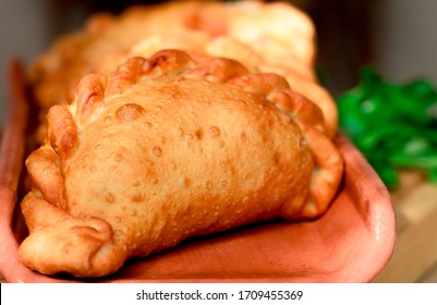 Traditional Cornish pasties decorated with parsely, on a wood plate
