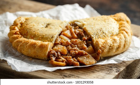 Traditional Cornish pasty filled with beef meat, potato and vegetables on black plate