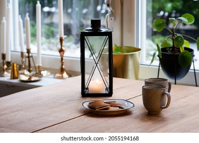 Traditional Cosy Christmas Coffee Break With Coffee Mugs And Gingerbread On The Wooden Table In The Kitchen With A Candle Light In A Lantern. Photo Taken In Sweden.