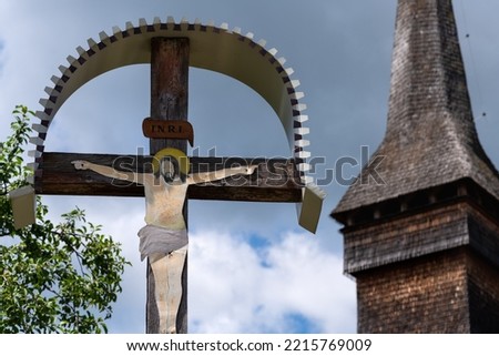 Traditional cross depicting Jesus with a wood church in the background in Maramures region of Romania. INRI refers to “Iesus Nazarenus, Rex Iudaeorum,” meaning “Jesus of Nazareth, King of the Jews.”