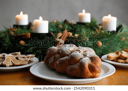 Traditional Czech and Slovak Christmas sweet plaited bread called vanocka (in Slovak vianocka), Christmas cookies and a Christmas advent wreath with four burning candles on wooden table.