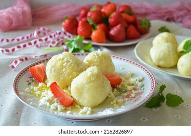 Traditionelle tschechische Süßknödel, gefüllt mit Erdbeeren ("jahodové knedlíky"), mit HartQuark, Zucker und geschmolzener Butter. Erdbeeren auf Hintergrund.