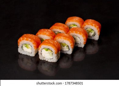 Traditional delicious fresh sushi roll set on a black background with reflection.  Sushi roll with rice, cream chees, red fish, salmon. Sushi menu. Japanese kitchen, restaurant. Seafood, asian food