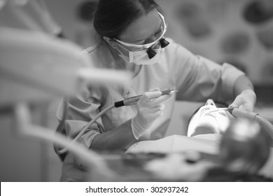 Traditional Dental Therapy; Female Dentist With A Drill And Suction Device In Hands