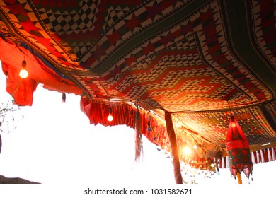 Traditional desert tent made of colorful patterned ethnic fabrics on wooden poles, decorated with lights and other gadgets, Rajastan India.