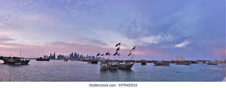Traditional Dhow boats carrying the Qatari flag in the skyline of Doha City 