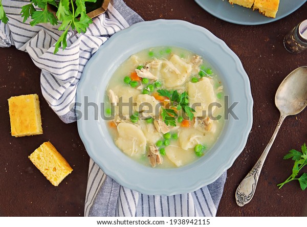 Traditional dish of\
the American South, dumplings and chicken, green peas in a gray\
ceramic plate on a brown concrete background. Family meals.\
American food. Served with\
cornbread