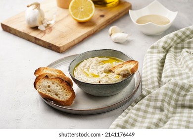 Traditional dish of arabic cuisine baba ganoush made of roasted eggplant, tahin, cilantro, garlic, olive oil, lemon juice with toasted baguette croutons on grey background - Shutterstock ID 2141176449
