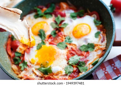 Traditional Dish Of Israeli Cuisine Shakshuka. Fried Eggs With Tomatoes, Peppers, Onions, Cilantro And Pita In A Pan.