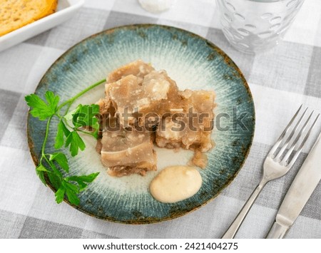 Traditional dish of Russian cuisine is a kholodets made from a jelly-like mass from cooling meat broth with pieces of meat. ..Served with sauce and garnished with a sprig of fresh parsley
