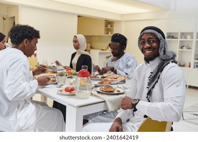 A traditional and diverse Muslim family comes together to share a delicious iftar meal during the sacred month of Ramadan, embodying the essence of familial joy, cultural richness, and spiritual unity - Powered by Shutterstock