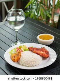 Traditional Dominican Meal, Rice With Steak, Ripe Plantain And Salad With A Glass Of Water And Pigeon Peas.