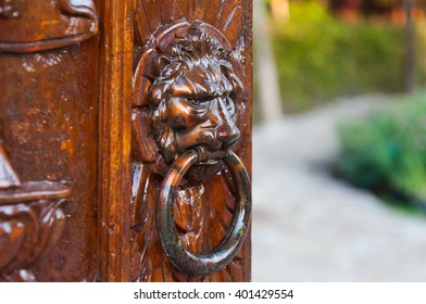 Traditional door knocker on a carve wooden door, iron made, showing the face of a lion