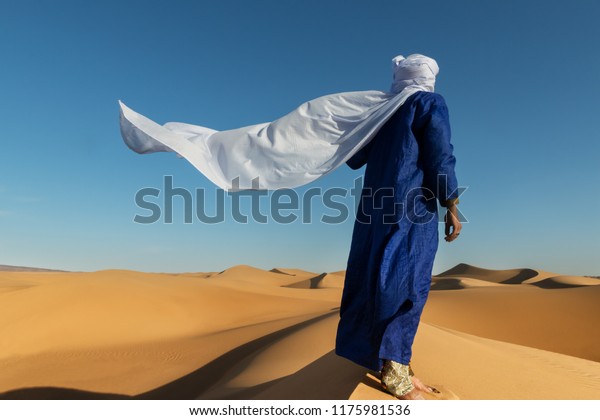 サハラ砂漠の砂丘の上に ターバンを持つ伝統的な服を着たモロッコ人男性が立つ の写真素材 今すぐ編集