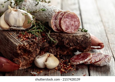 Traditional dry-cured sausage with thyme, garlic, onion, and spices. Dry-cured sausage on a old wooden table.