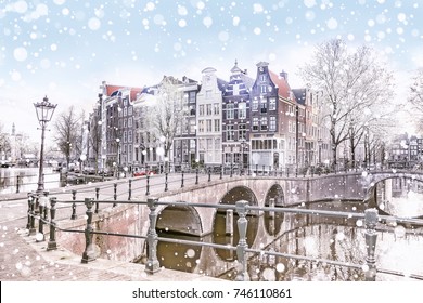 Traditional Dutch old houses and bridges on the canals in Amsterdam on a snowy winter night, The Netherlands