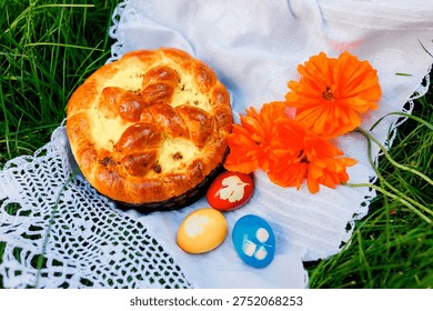 Pan de Pascua tradicional con huevos de colores y flores en tela blanca al aire libre.