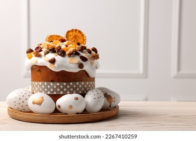 Traditional Easter cake with dried fruits and decorated eggs on white wooden table indoors. Space for text