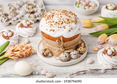 Traditional Easter Cake Or Sweet Bread, Quail Eggs, White Meringues In Shape Of Nest, Pussy Willow Twigs And Spring Flowers Over White Wooden Table. Side View. Easter Treat, Holiday Symbol