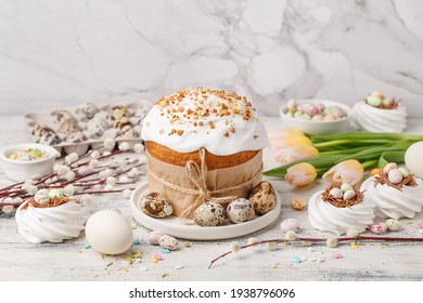 Traditional Easter Cake Or Sweet Bread, Quail Eggs, White Meringues In Shape Of Nest, Pussy Willow Twigs And Spring Flowers Over White Wooden Table. Side View. Easter Treat, Holiday Symbol