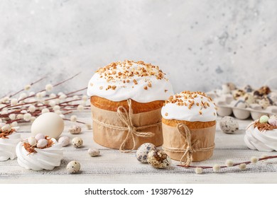 Traditional easter cake or sweet bread, pussy willow twigs, quail eggs and white meringues in shape of nest over white wooden table. Side view, close up. Easter treat, holiday symbol