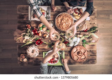 Traditional Easter celebration, Easter holiday party. Holiday friends or family at the festive table with rabbit meat, vegetables, pies, eggs, top view. Friends hands eating and drinking together.