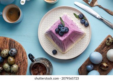 Traditional Easter Orthodox curd cake with blueberry. Traditional Easter cottage cheese dessert. Flowers, blueberry, eggs. Blue background, top view, horizontally