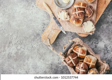 Traditional Easter treats cross buns with raisins, served with fresh butter on the grey stone board. Top view