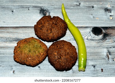 Traditional Egyptian Fried Falafel Balls, Green Burger, Made Of Ground Chickpeas And Broad Beans, Deep Fried Balls Or Patty-shaped Fritter With Chili Green Fresh Pepper Isolated On Wood Background