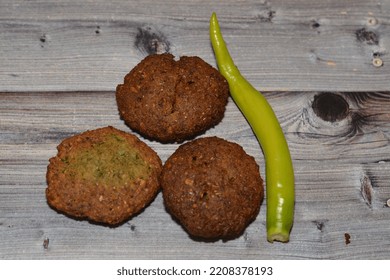 Traditional Egyptian Fried Falafel Balls, Green Burger, Made Of Ground Chickpeas And Broad Beans, Deep Fried Balls Or Patty-shaped Fritter With Chili Green Fresh Pepper Isolated On Wood Background