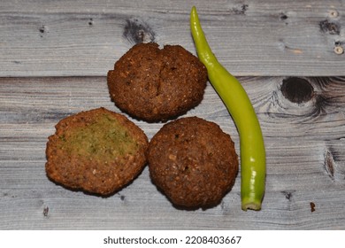 Traditional Egyptian Fried Falafel Balls, Green Burger, Made Of Ground Chickpeas And Broad Beans, Deep Fried Balls Or Patty-shaped Fritter With Chili Green Fresh Pepper Isolated On Wood Background