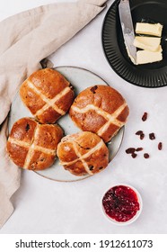 Traditional English Easter Hot Cross Buns on a plate with jam, raisins and butter, top view