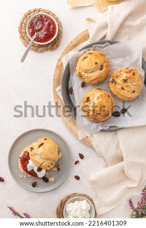 Traditional English pastries for afternoon tea: scones. Homemade raisin scones with clotted cream and homemade strawberry jam. Scones on plate served with milk on table. Top view. Flat lay
